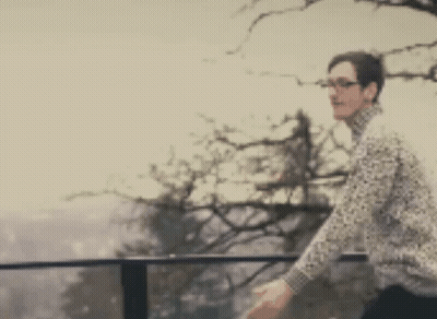 A Blurry Picture Of A Man Standing On A Balcony With A Tree In The Background GIF