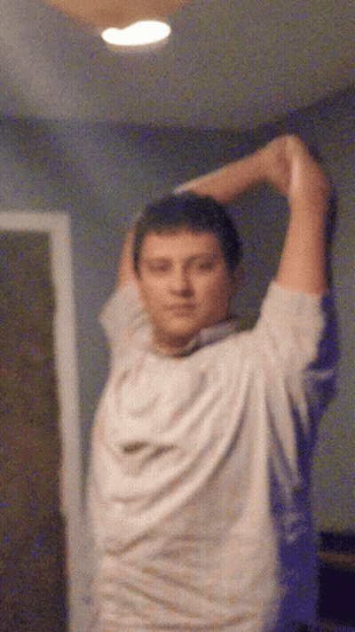 A Blurry Picture Of A Man Stretching His Arms In A Room GIF