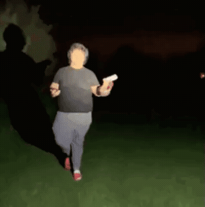 A Blurry Picture Of A Man Walking In The Dark Holding A Frisbee . GIF