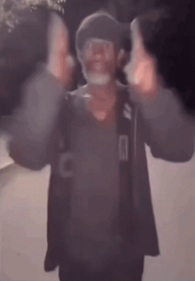 A Blurry Picture Of A Man Wearing A Mask And A Hat Giving The Middle Finger . GIF