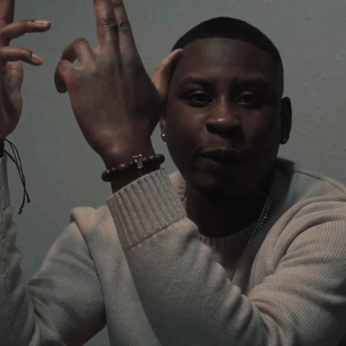 A Blurry Picture Of A Man Wearing A White Shirt And A Necklace GIF