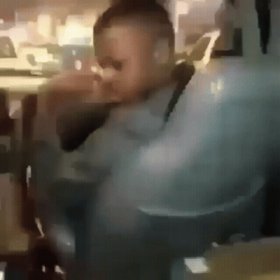 A Blurry Picture Of A Man Wearing Sunglasses Sitting In A Chair . GIF
