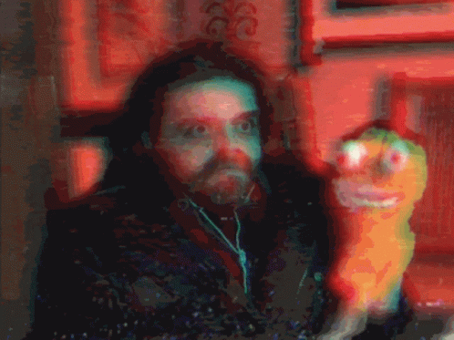 A Blurry Picture Of A Man With Ear Buds And A Stuffed Animal GIF