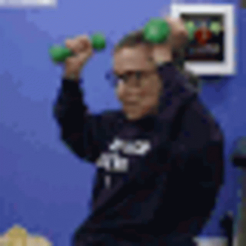 A Blurry Picture Of A Person Holding A Green Dumbbell In Their Hands . GIF