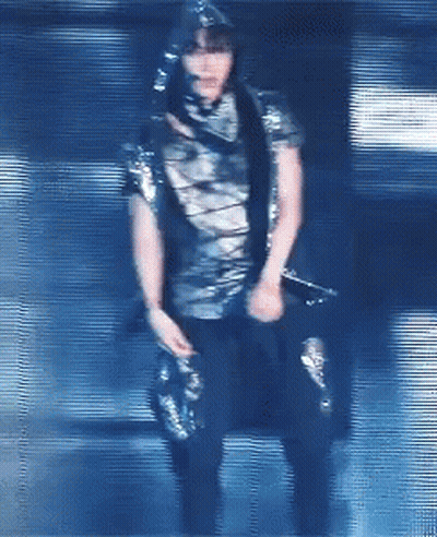 A Blurry Picture Of A Person Holding A Microphone In A Dark Room GIF