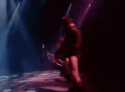 A Blurry Picture Of A Person Holding A Microphone In A Dark Room GIF