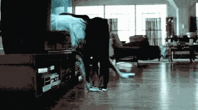 A Blurry Picture Of A Person In A Living Room With A Tv In The Background GIF