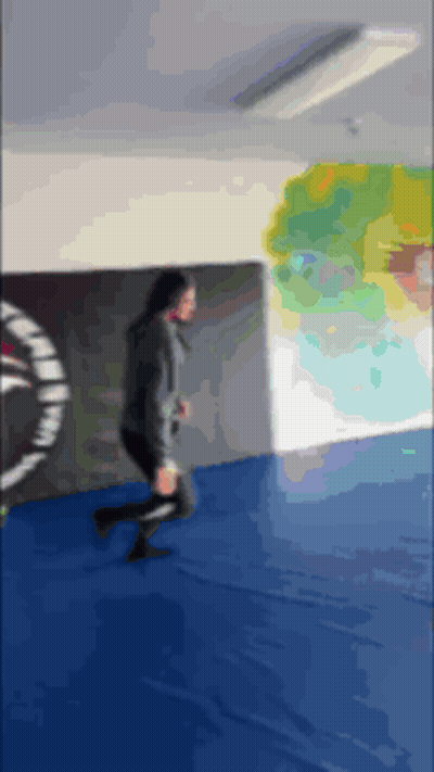 A Blurry Picture Of A Person Running On A Blue Mat In A Gym GIF