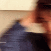 A Blurry Picture Of A Person 'S Face With A Blue Jacket On GIF