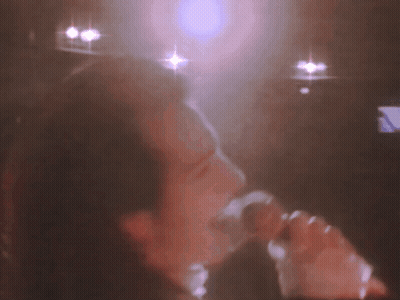 A Blurry Picture Of A Person Singing Into A Microphone . GIF