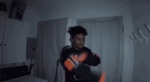 A Blurry Picture Of A Person Standing In A Dark Room With Their Hands Up . GIF