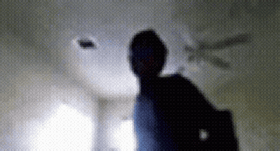 A Blurry Picture Of A Person Standing In A Room With A Ceiling Fan In The Background . GIF