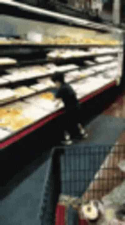 A Blurry Picture Of A Person Standing In Front Of A Display Of Food In A Grocery Store . GIF