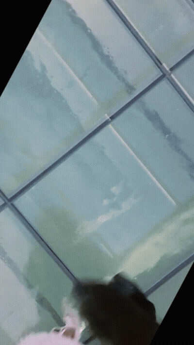 A Blurry Picture Of A Person Standing On A Glass Ceiling GIF