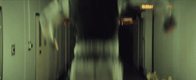 A Blurry Picture Of A Person Walking Down A Hallway With A Sign That Says Emergency Exit GIF