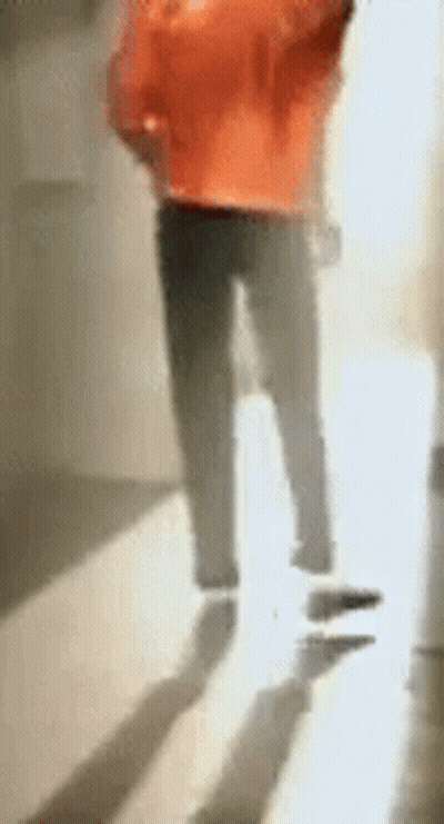 A Blurry Picture Of A Person Walking Down A Hallway With Their Shadow On The Floor . GIF