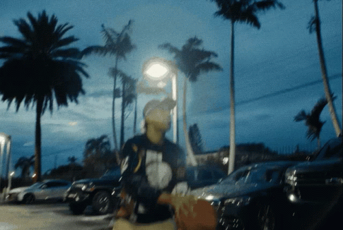 A Blurry Picture Of A Person Walking In A Parking Lot GIF