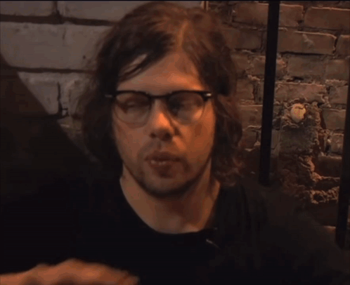 A Blurry Picture Of A Person Wearing Glasses And Giving A Rock Sign GIF