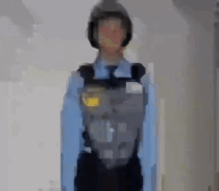 A Blurry Picture Of A Police Officer Wearing A Helmet And A Blue Shirt . GIF