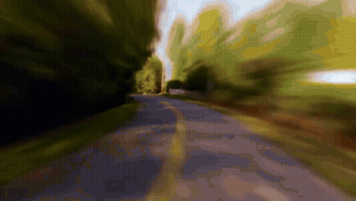 A Blurry Picture Of A Road Going Through A Forest GIF