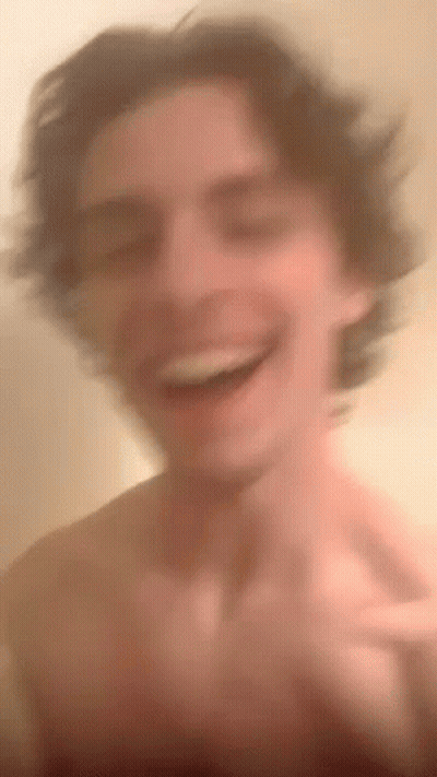 A Blurry Picture Of A Shirtless Man Laughing And Smiling . GIF