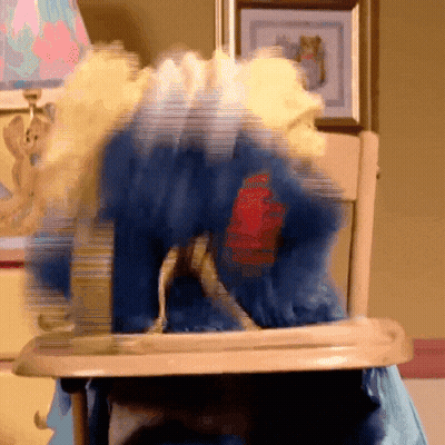 A Blurry Picture Of A Stuffed Animal In A High Chair With A Red Heart On Its Chest GIF