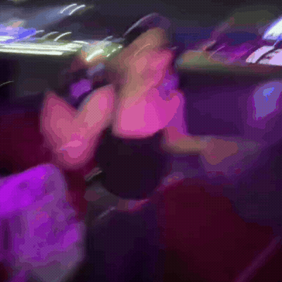 A Blurry Picture Of A Woman Dancing In A Club With A Chair In The Foreground GIF