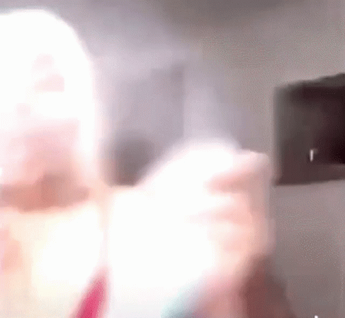 A Blurry Picture Of A Woman Holding A Light Bulb In Her Hand . GIF