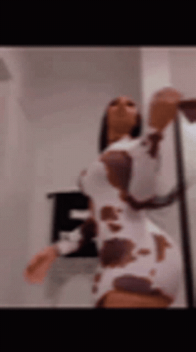 A Blurry Picture Of A Woman In A Cow Print Dress Dancing . GIF