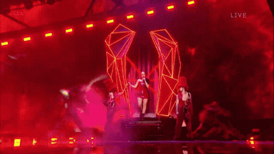 A Blurry Picture Of A Woman In A Red Dress On A Stage With Itv Live In The Lower Right Corner GIF