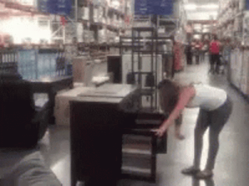 A Blurry Picture Of A Woman In A Store Looking At A Table GIF