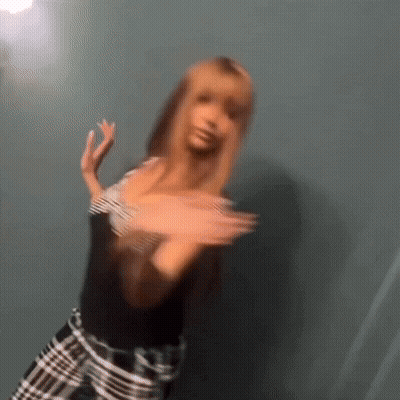 A Blurry Picture Of A Woman Wearing A Black Shirt And Plaid Pants GIF
