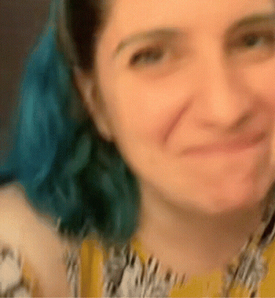 A Blurry Picture Of A Woman With Blue Hair And A Yellow Shirt GIF