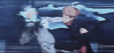 A Blurry Picture Of Two People Fighting Each Other In A Dark Room GIF