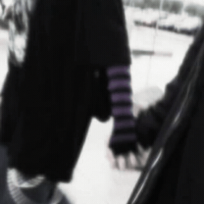 A Blurry Picture Of Two People Holding Hands . One Of The People Is Wearing Purple Striped Sleeves . GIF