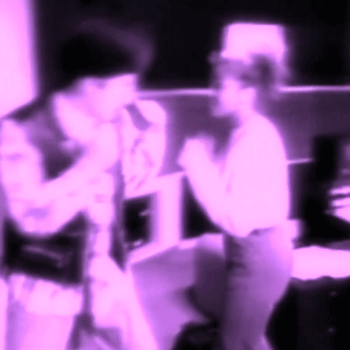 A Blurry Picture Of Two People Standing Next To Each Other In Purple Lighting GIF