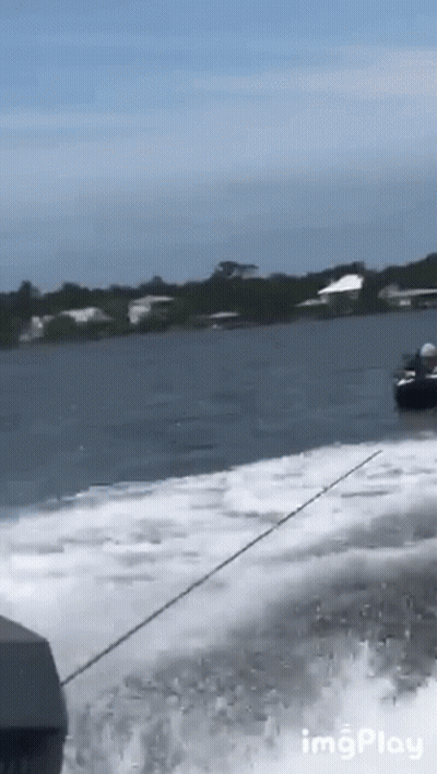 A Boat Is Going Through A Body Of Water With Houses In The Background GIF