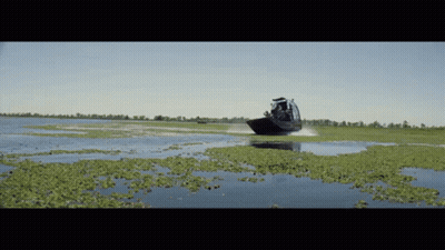 A Boat Is Going Through A Swamp With A Lot Of Plants GIF