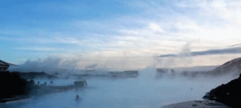 A Body Of Water With A Blue Sky And Clouds Behind It GIF