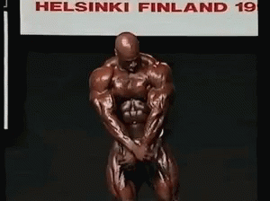 A Bodybuilder Kneeling In Front Of A Sign That Says Helsinki Finland 19 GIF