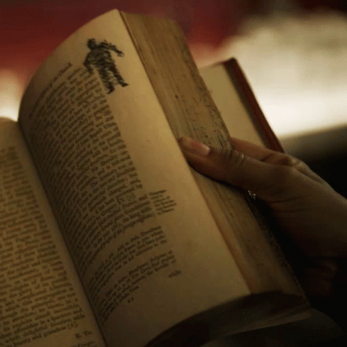 A Book Is Open To A Page With A Silhouette Of A Person On It GIF