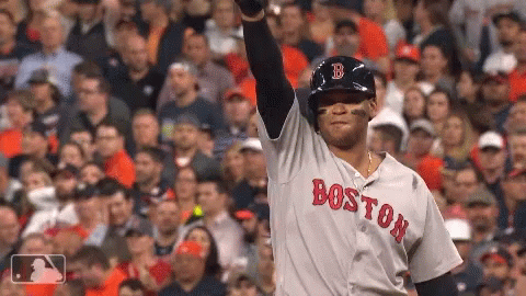A Boston Baseball Player Stands In Front Of A Crowd With His Arm In The Air GIF