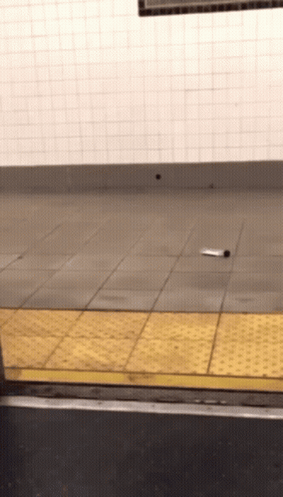 A Bottle Is Laying On A Tiled Floor Next To A Yellow Curb GIF