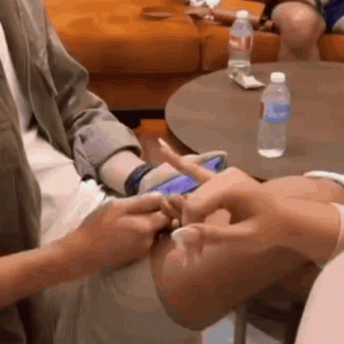 A Bottle Of Aquafina Water Sits On A Table Next To A Person 'S Hand GIF