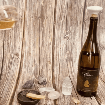 A Bottle Of Chardonnay Sits On A Wooden Surface GIF