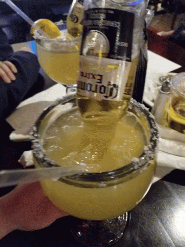 A Bottle Of Corona Is Being Poured Into A Margarita Glass GIF