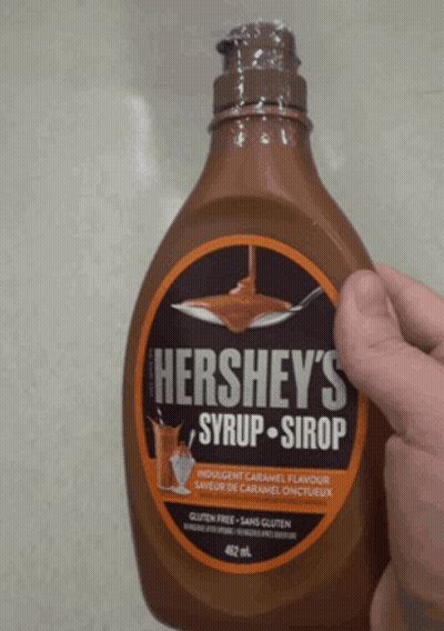 A Bottle Of Hershey 'S Syrup Is Being Held By A Hand GIF