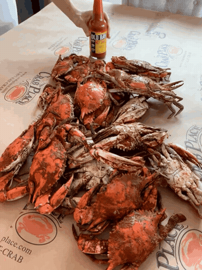 A Bottle Of Hot Sauce Is Being Poured Over Crabs GIF