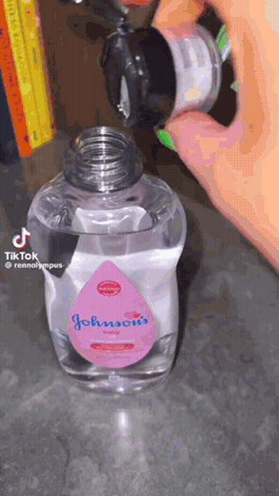 A Bottle Of Johnson 'S Baby Oil Is Being Poured Into Another Bottle GIF