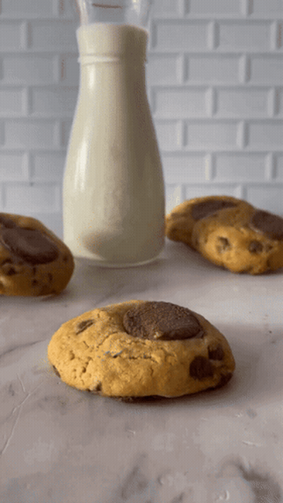A Bottle Of Milk Sits Next To Three Cookies GIF